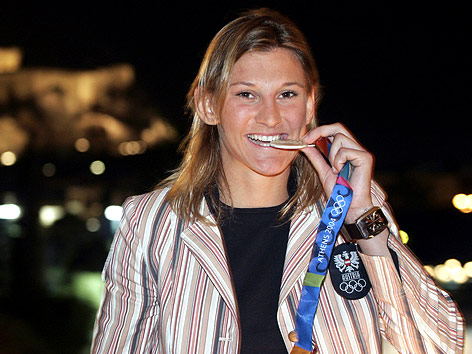 © GEPA/Dominic Ebenbichler Claudia Heill beißt in ihre Olympiamedaille.