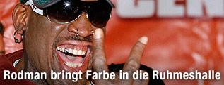 Dennis Rodman mit Sonnenbrille und Kappe zeigt ein Victory-Zeichen