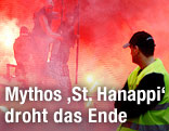 Ein Ordner beobachtet am Zaun h&auml;ngende Rapid-Fans, umgeben vom roten Rauch des bengalischen Feuers