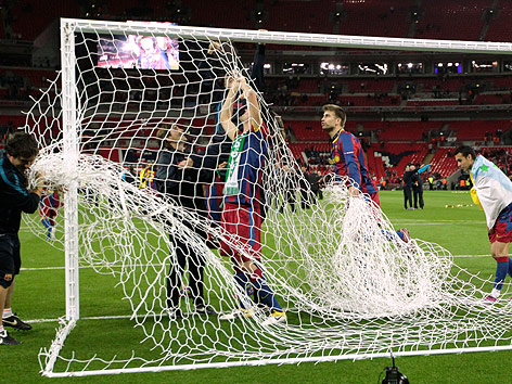 © AP/Matt Dunham Gerard Pique (Barcelona) schneidet mit seinen Teamkollegen das Netz aus dem Tor.