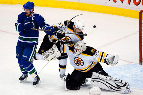 Boston Bruins Johnny Boychuk wird von Vancouver Canucks Henrik Sedin vor dem Tor von Goalie Tim Thomas zu Fall gebracht.