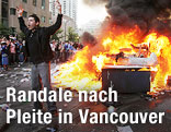Canucks-Fan steht mit erhobenen H&auml;nden neben einem brennenden Pick-Up