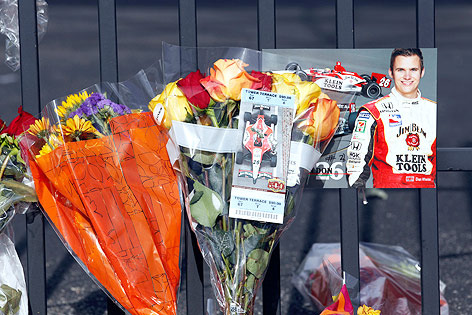 © AP/Michael Conroy Blumen vor einem Bild des verunglückten Rennfahrers Dan Wheldon