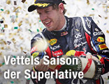 Sebstian Vettel lässt im Konfettiregen Champagner aus einer Flasche spritzen