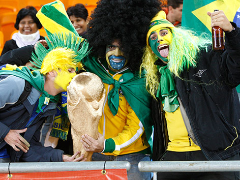 © GEPA/Christian Ort Verkleidete Brasilien-Fans mit Fahne, Bierflasche und WM-Pokal in den Händen