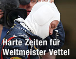 Red-Bull-Pilot Sebastian Vettel zieht sich enttäuscht seine feuerfeste Haube vom Kopf