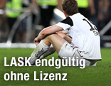 Entt&auml;uschter LASK-Spieler sitzt am Spielfeld mit dem R&uuml;cken zur Kamera