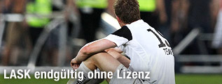 Enttäuschter LASK-Spieler sitzt am Spielfeld mit dem Rücken zur Kamera