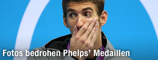 Michael Phelps h&auml;lt sich bei der Siegerzeremonie in London die Hand vor seinem Mund