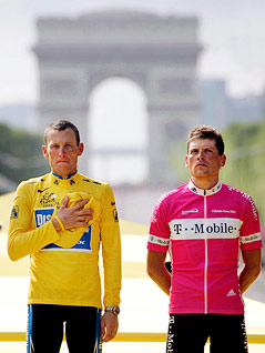 © APA/EPA/Gero Berloer Lance Armstrong und Jan Ullrich stehen auf einem Podest vor dem Triumphbogen in Paris