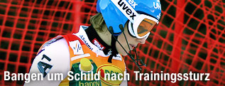 Marlies Schild mit Slalomhelm vor einem Absperrnetz