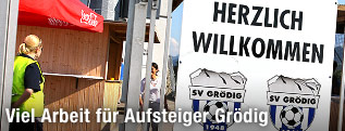Schild mit der Aufschrift "Herzlich Willkommen" und dem Gr&ouml;dig-Logo