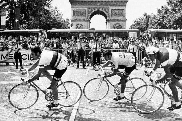 © AP Eddie Merckx (BEL), Bernard Thevene und Regis Ovion (beide FRA) passieren den Triumphbogen in Paris im Juli 1975