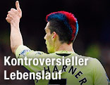 Paul Scharner von hinten mit rot-blau-gefärbten Haaren zeigt mit dem Daumen nach oben