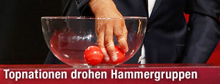 Hand greift in eine Sch&uuml;ssel mit den Loskugeln