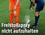 Ein Schiedsrichter sprayt eine Linie mit Schaum auf den Rasen
