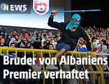 Ein vermummter Mann mit Stange &uuml;berspringt eine Stadionabsperrung