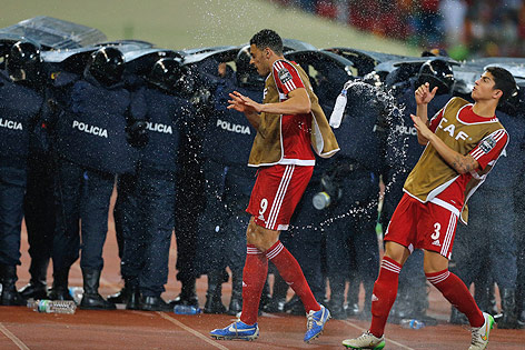 © Reuters/Amr Abdallah Dalsh Spieler von Äquatorialguinea werden mit Wasserflaschen beworfen während die Polzei Spieler aus Ghana schützt