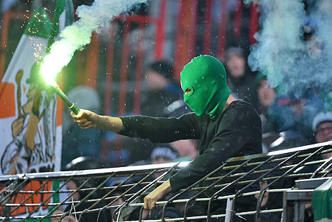 © GEPA/Martin Hörmandinger Person mit grüner Maske und bengalischem Feuer