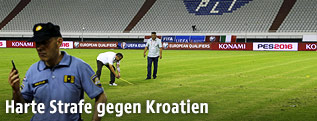 Polizisten vermessen die Größe des Hakenkreuzes auf dem Fußballrasen