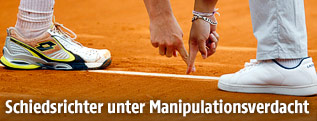 Anonymer Tennis-Spieler und Schiedsrichter deuten auf eine Grundlinie
