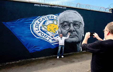 Ein Fan lässt sich vor einem gemalten Porträt von Leicester-Trainer Claudio Ranieri fotografieren