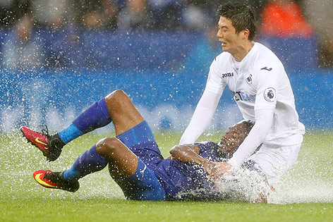 © Reuters/Action Images/Carl Recine Spieler rutschen bei der Partie Leicester City - Swansea über den regennassen Rasen