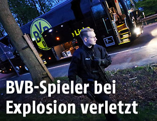 Polizist vor dem durch die Explosionen beschädigten Mannschaftsbus