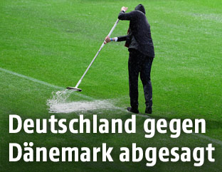 Ordner versuchen Wasser vom Rasen zu kehren