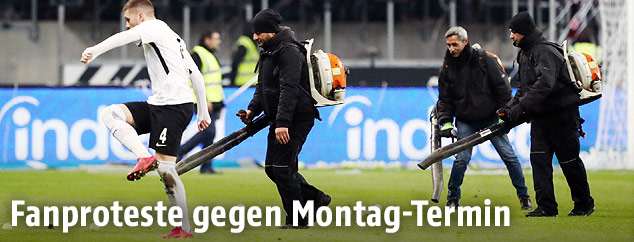 Mann mit Laubsauger auf Fußballfeld